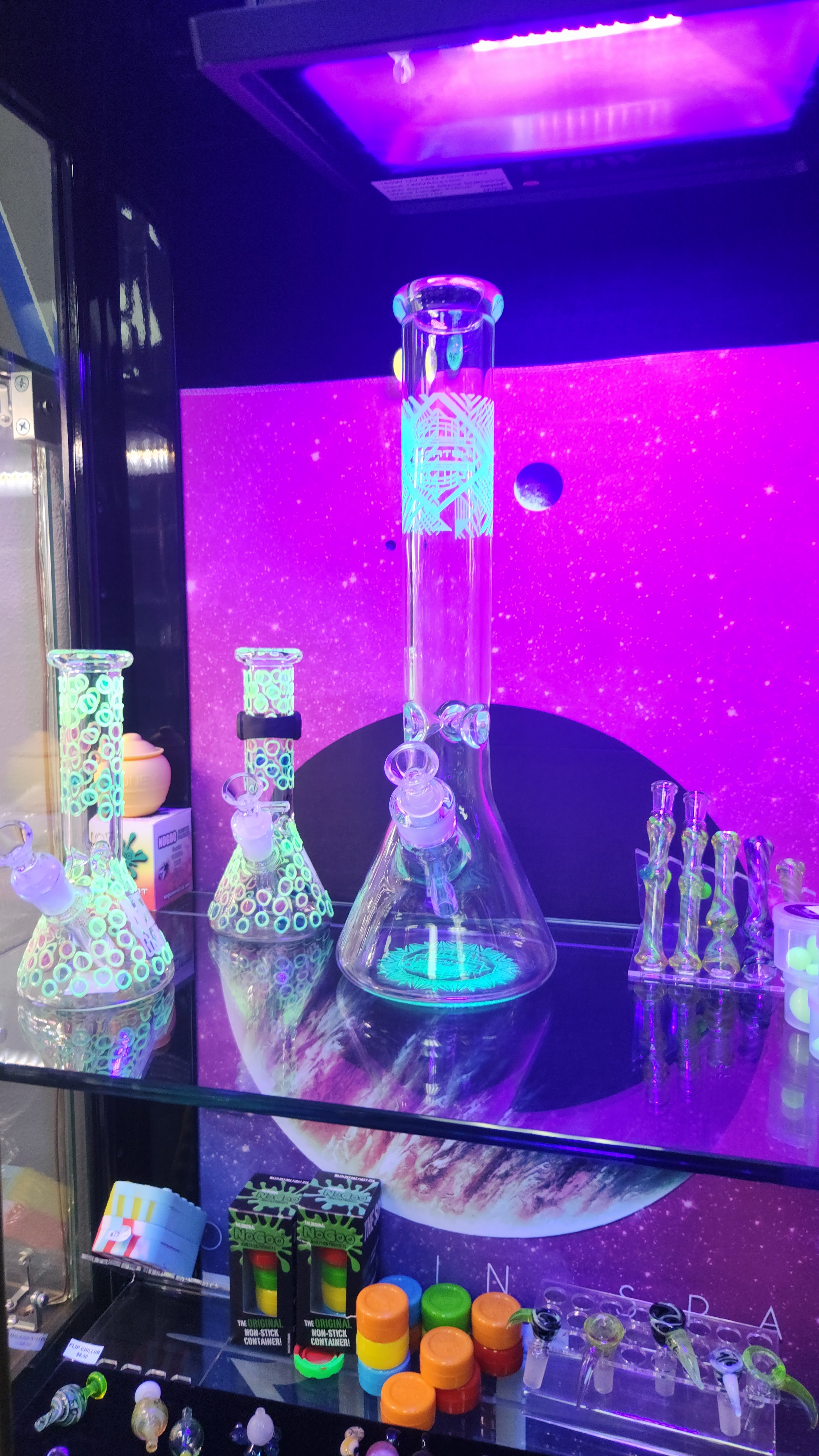 Neon-lit display of glass pipes and accessories